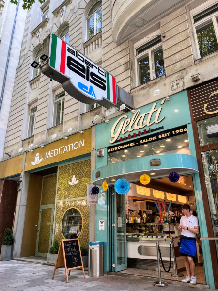 Alberti Eis Gelati Shop storefront in Vienna. A worker stands at the entryway, open to welcome customers.